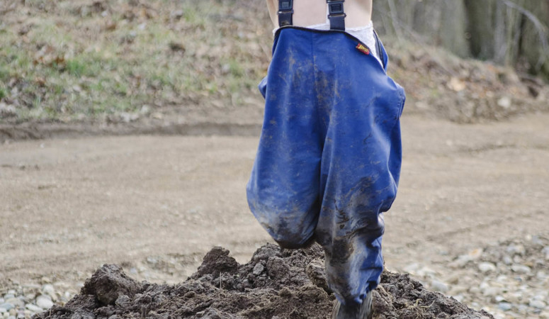Child jumping in a pile of dirt.