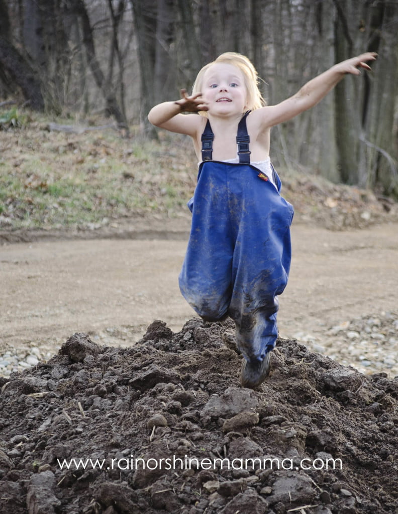 Child jumping in a pile of dirt.