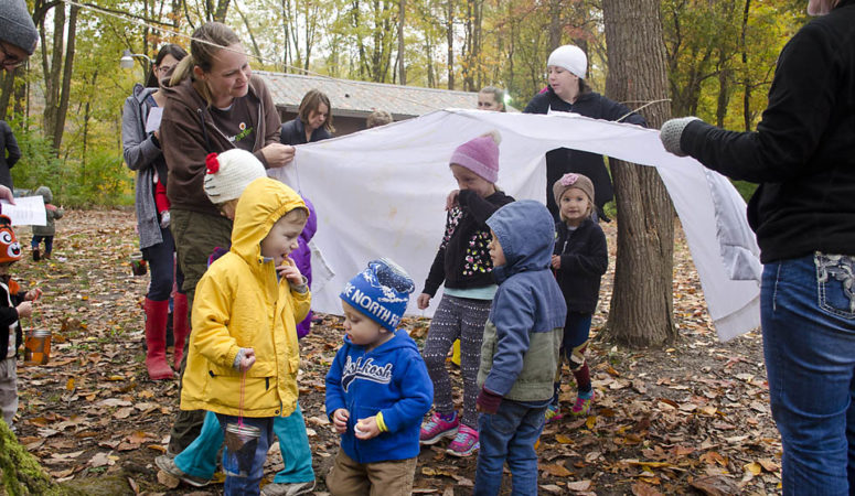 Tinkergarten leader Marissa Northam uses a sheet to create a tunnel for the children in her class in Terre Haute, Ind.